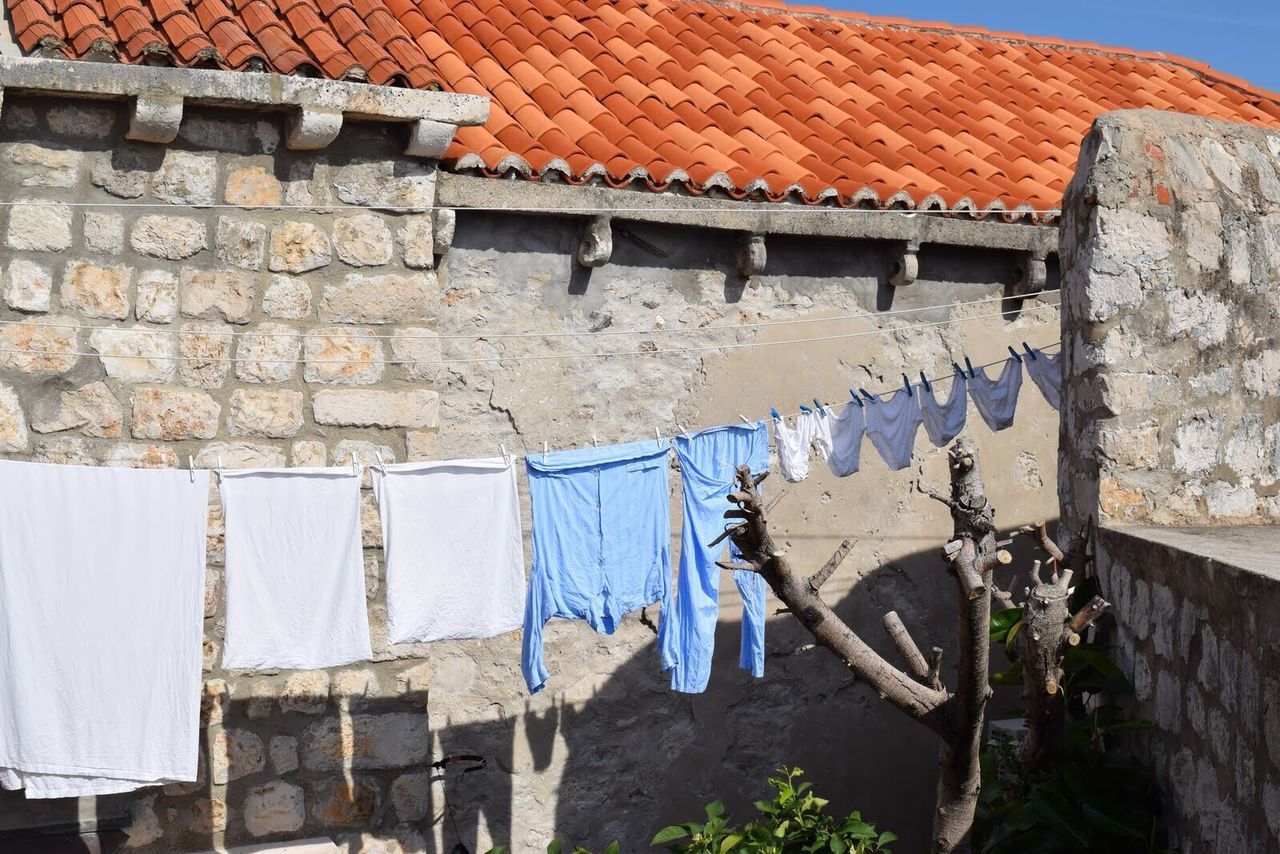 Clothes hanging on clothesline by brick wall
