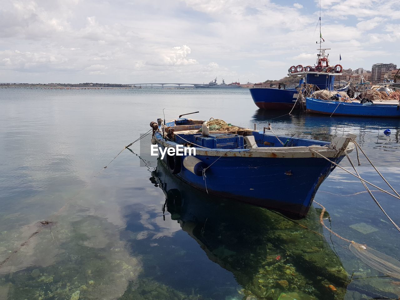 Boats moored at harbor against cloudy sky