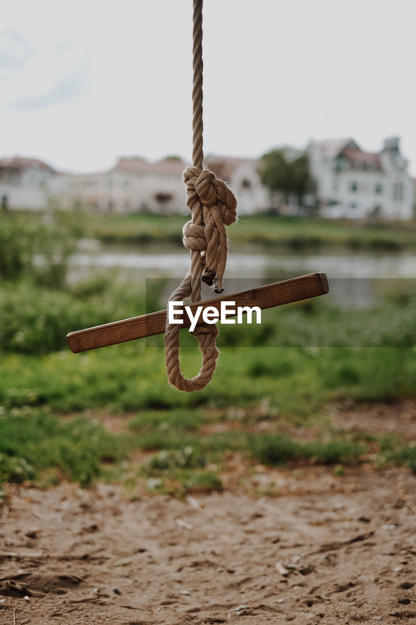 CLOSE-UP OF ROPE TIED UP ON RUSTY METAL CHAIN