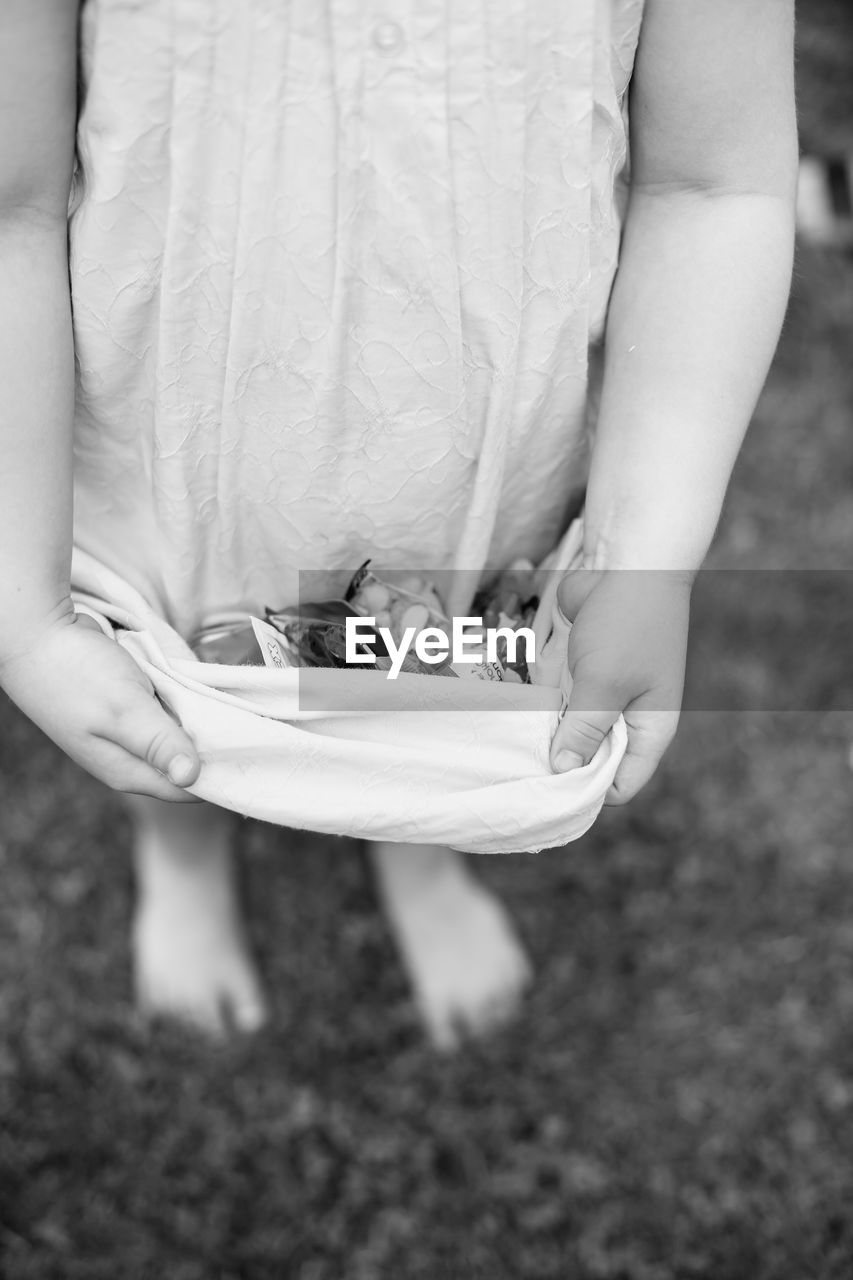 Midsection of girl carrying objects with her dress