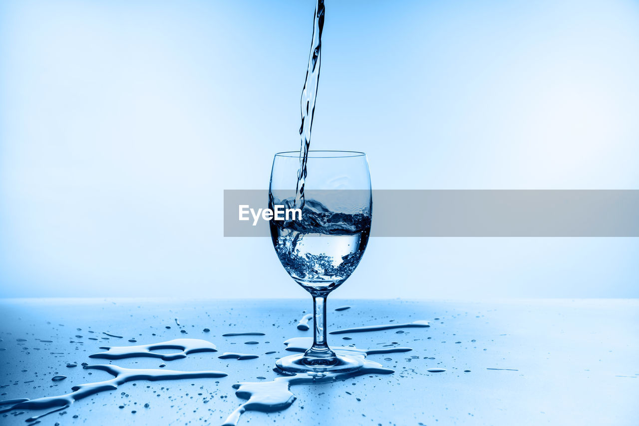 CLOSE-UP OF GLASS POURING WATER