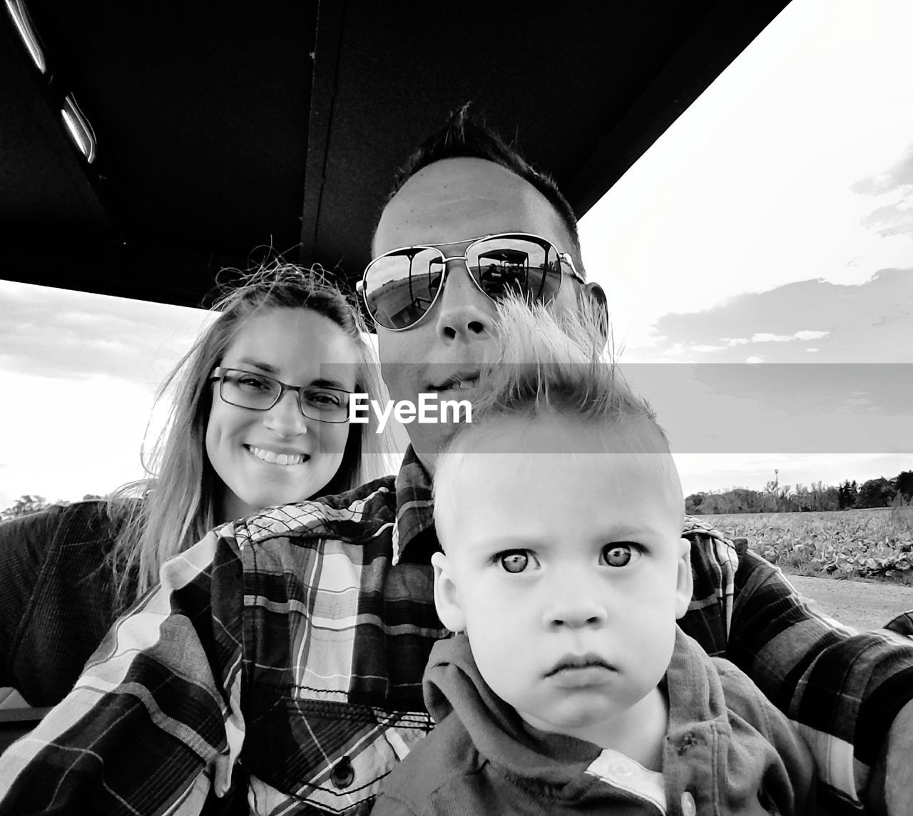 Portrait of happy family in vehicle against sky