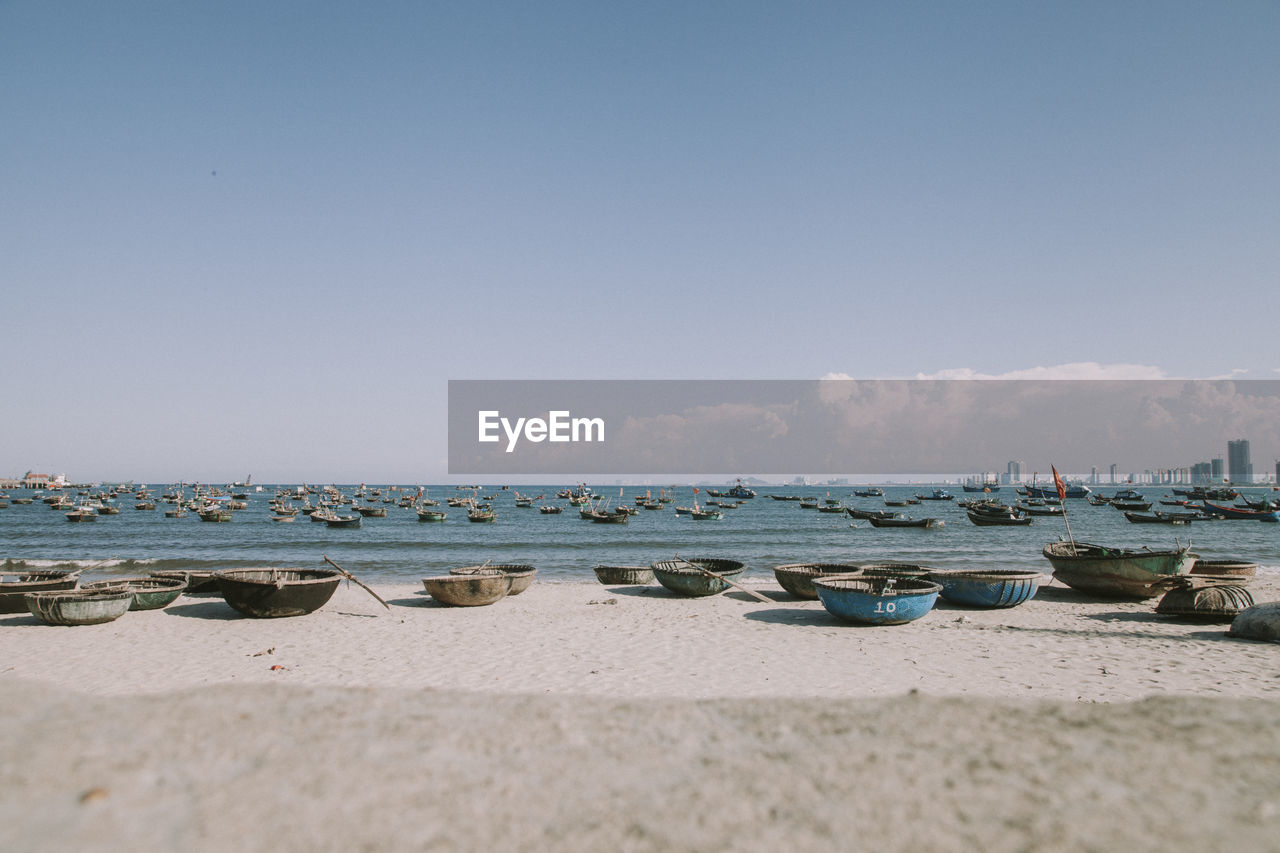 BOATS MOORED ON SHORE AGAINST SKY