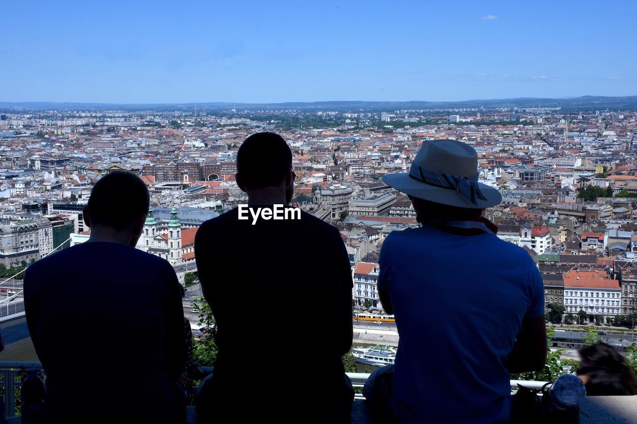 REAR VIEW OF MAN AND CITYSCAPE IN BACKGROUND