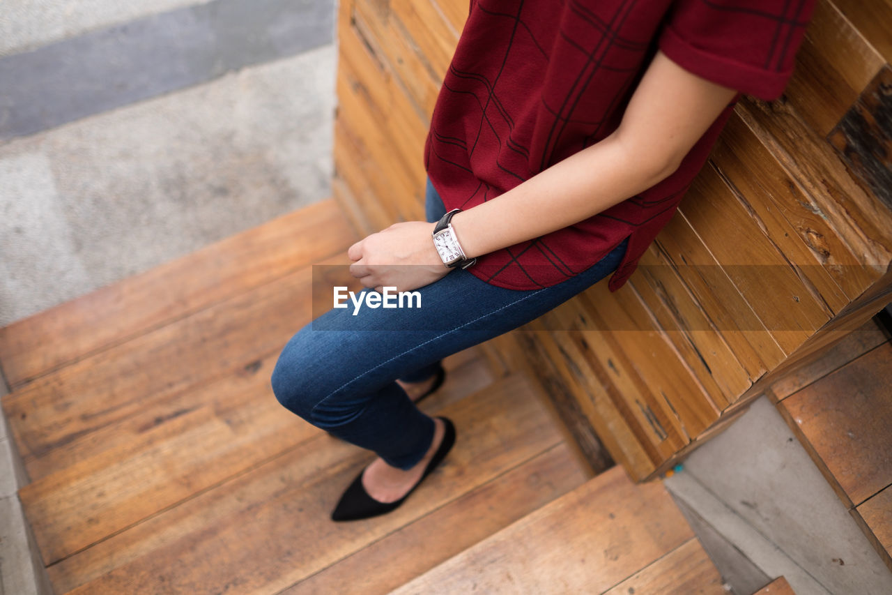 Low section of woman sitting on hardwood floor