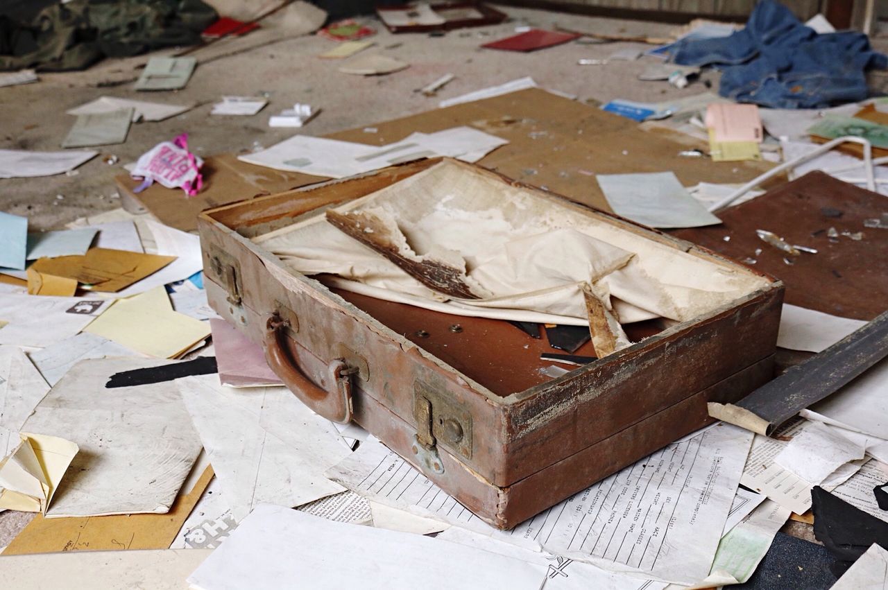 High angle view of abandoned briefcase with documents on floor