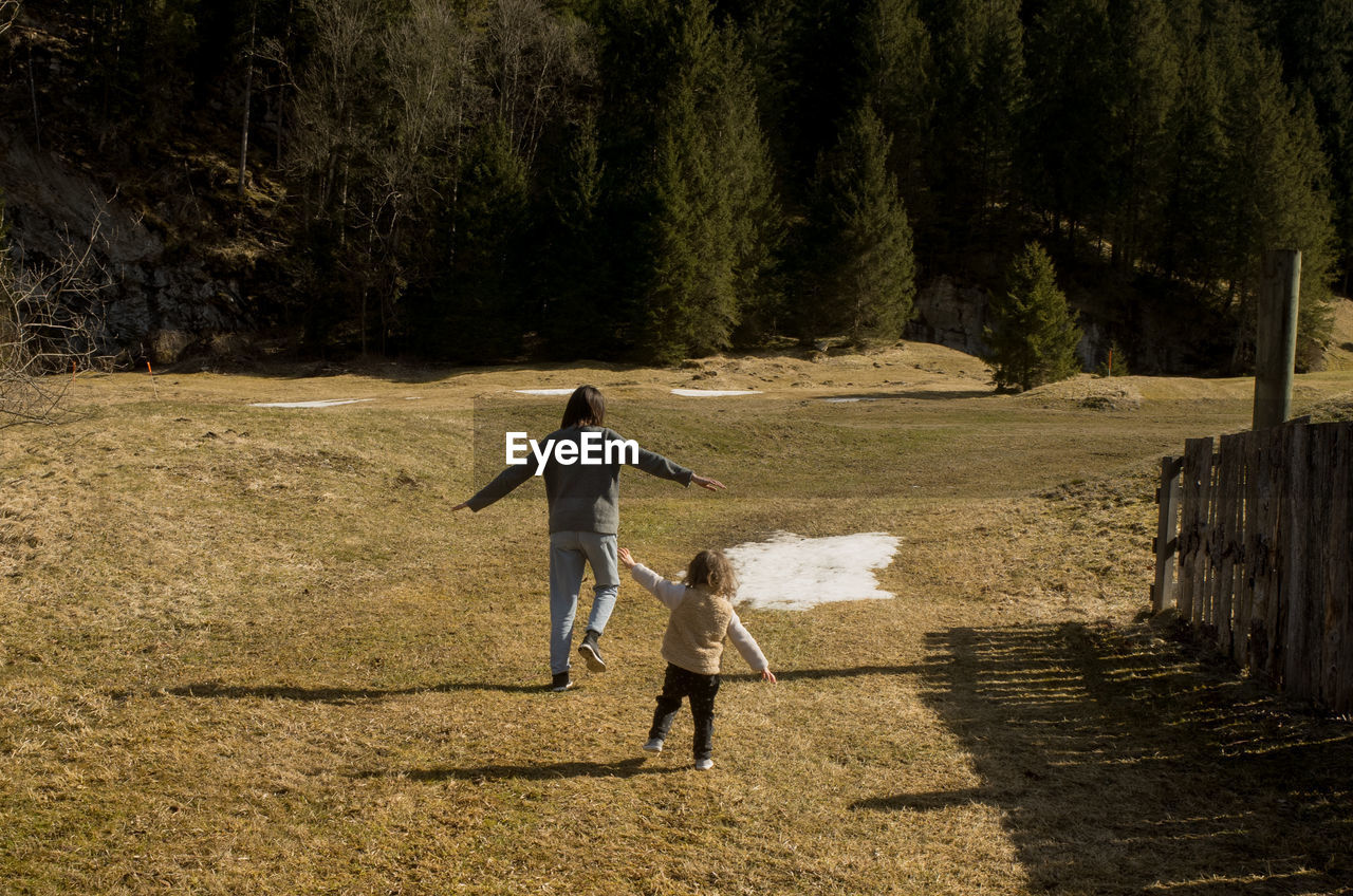 REAR VIEW OF MAN WALKING ON FIELD