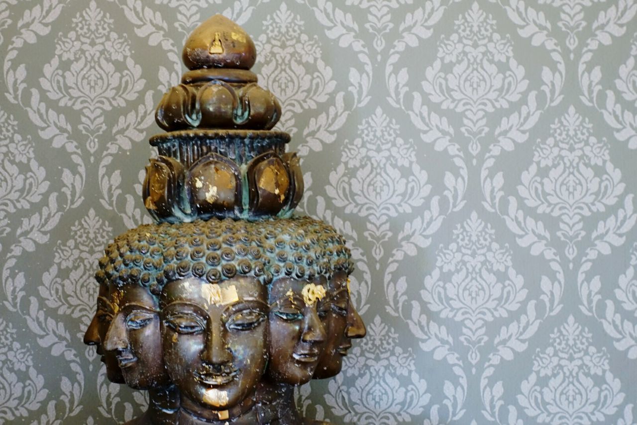 Old damaged buddha statue against wallpaper
