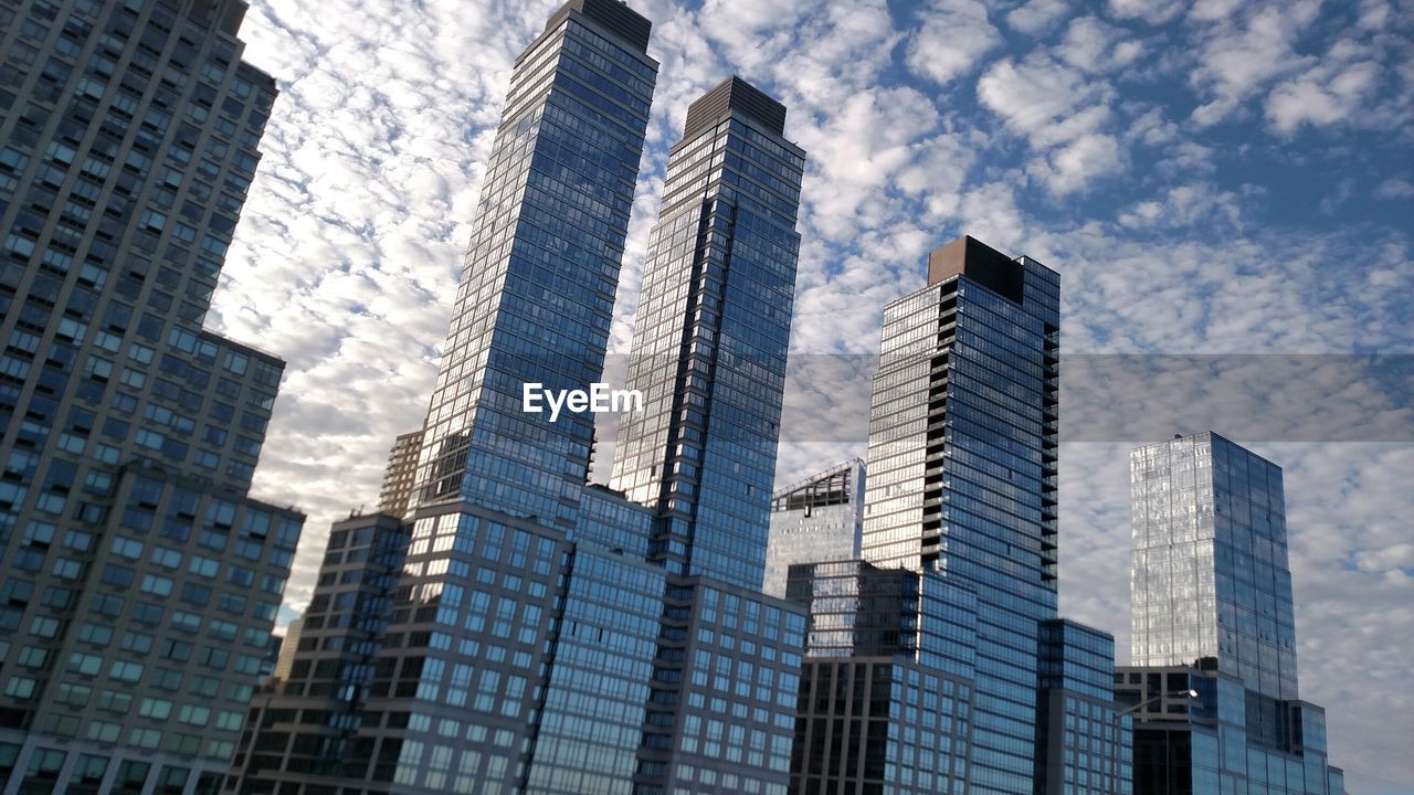 Low angle view of modern buildings against cloudy sky