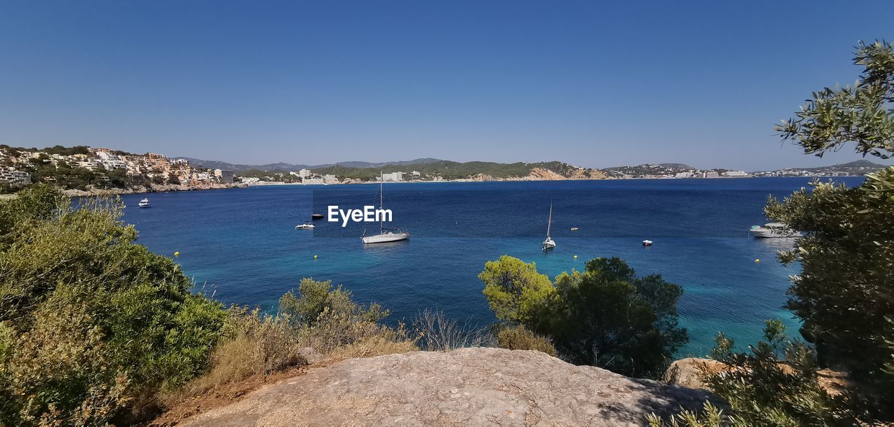 Scenic view of bay against clear blue sky