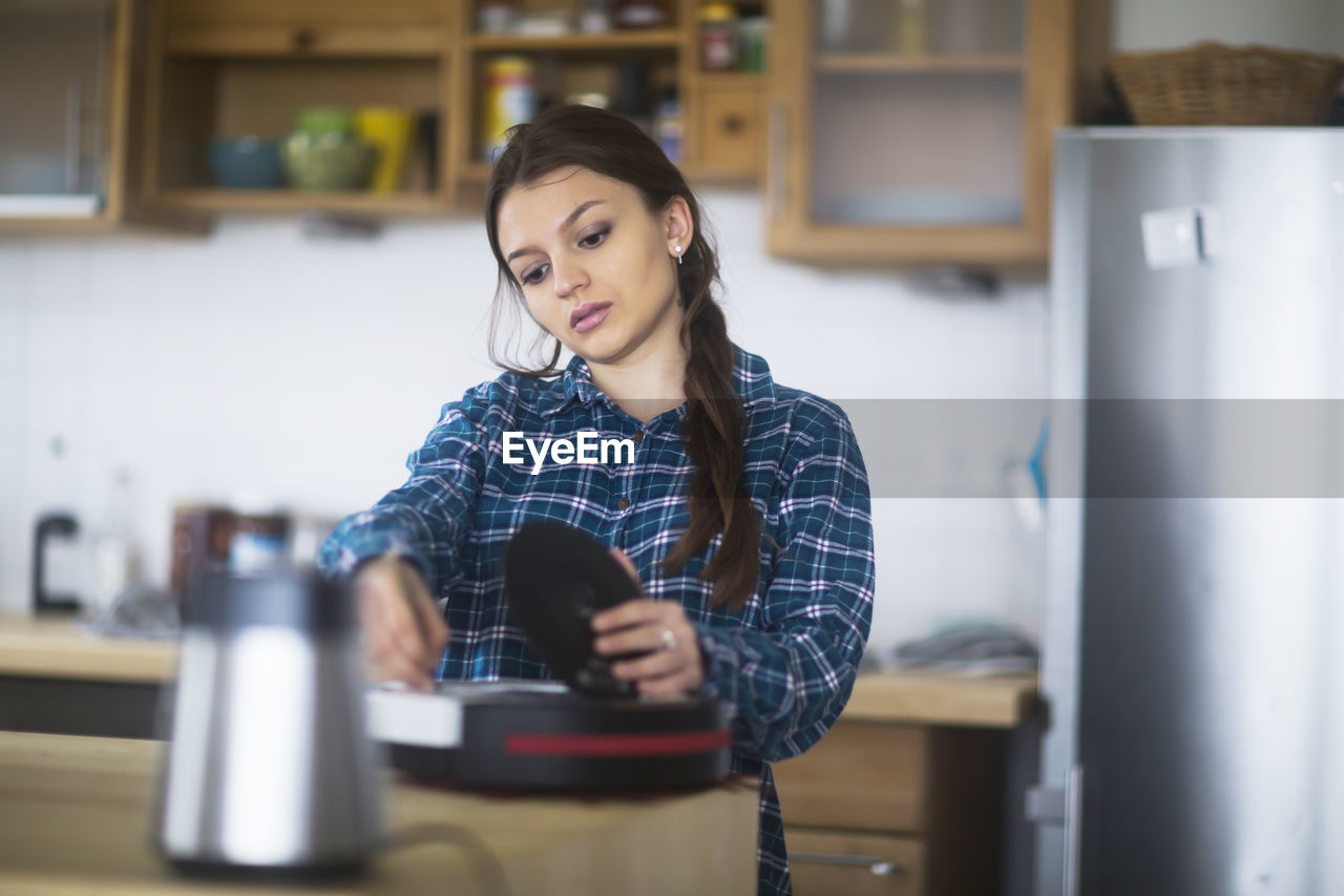 Young woman cleaning an untensil in the kitchen