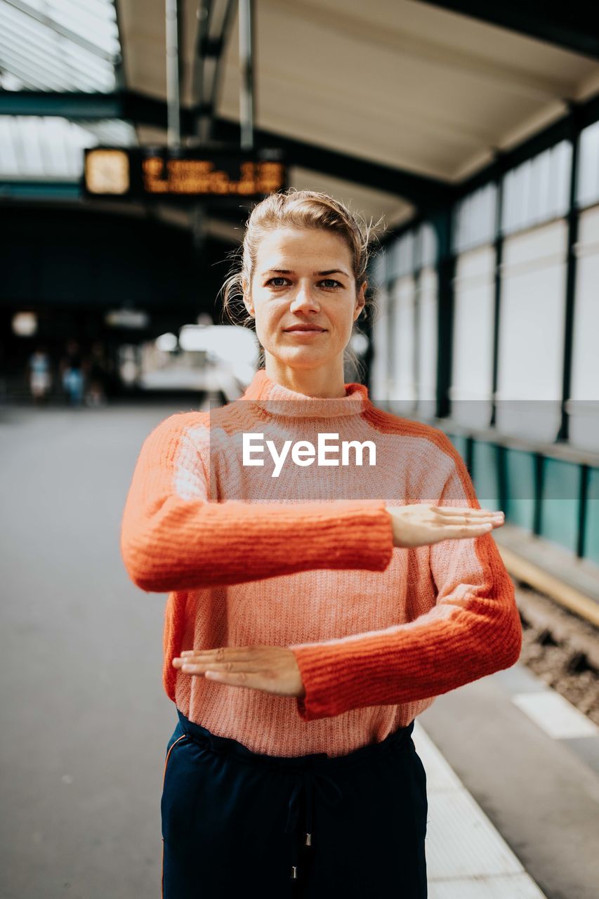 PORTRAIT OF WOMAN STANDING AGAINST BLURRED BACKGROUND