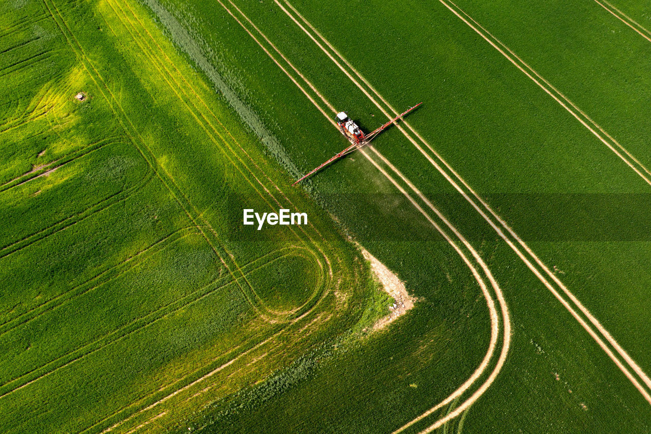 Top down view of the tractor spraying the chemicals on the large green field