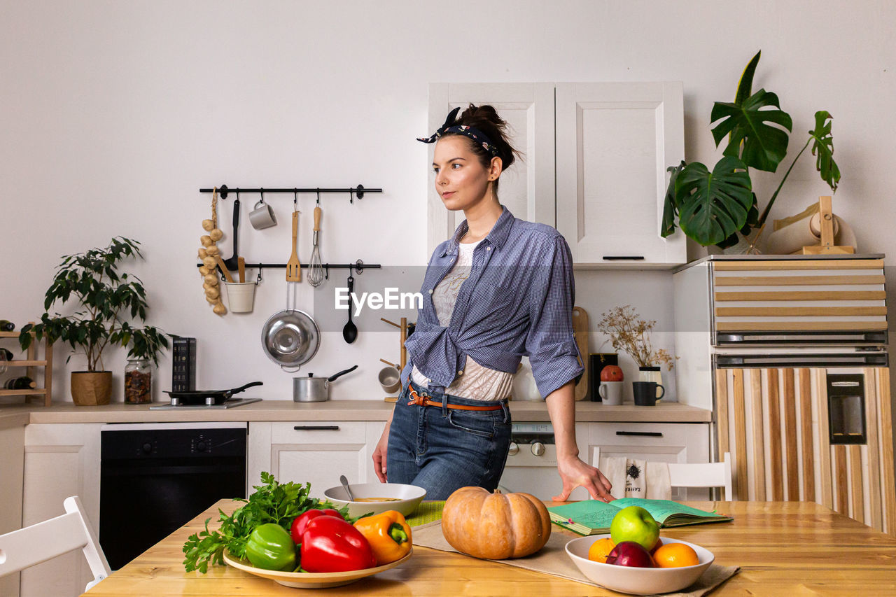 Young and beautiful housewife woman cooking in a white kitchen