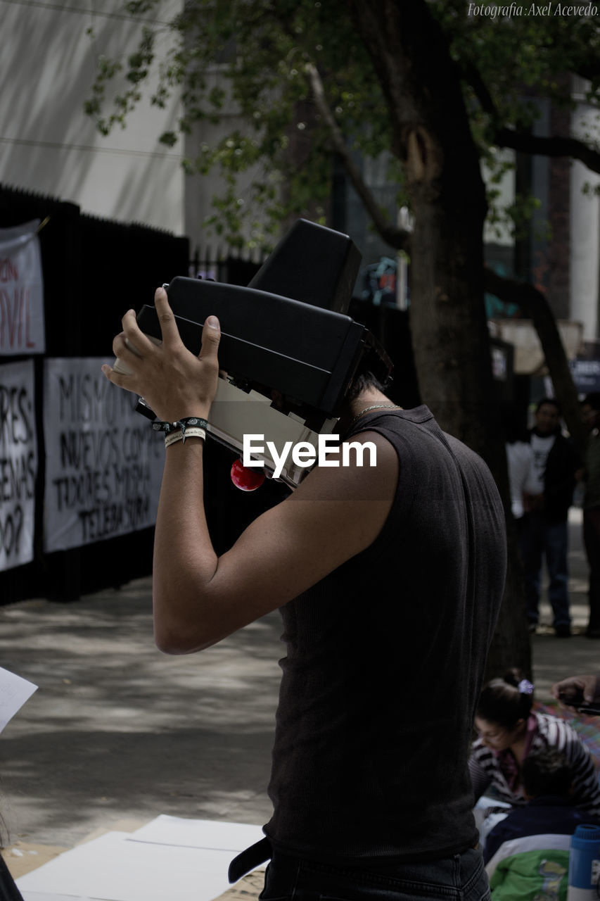 Side view of man covering face while standing in city