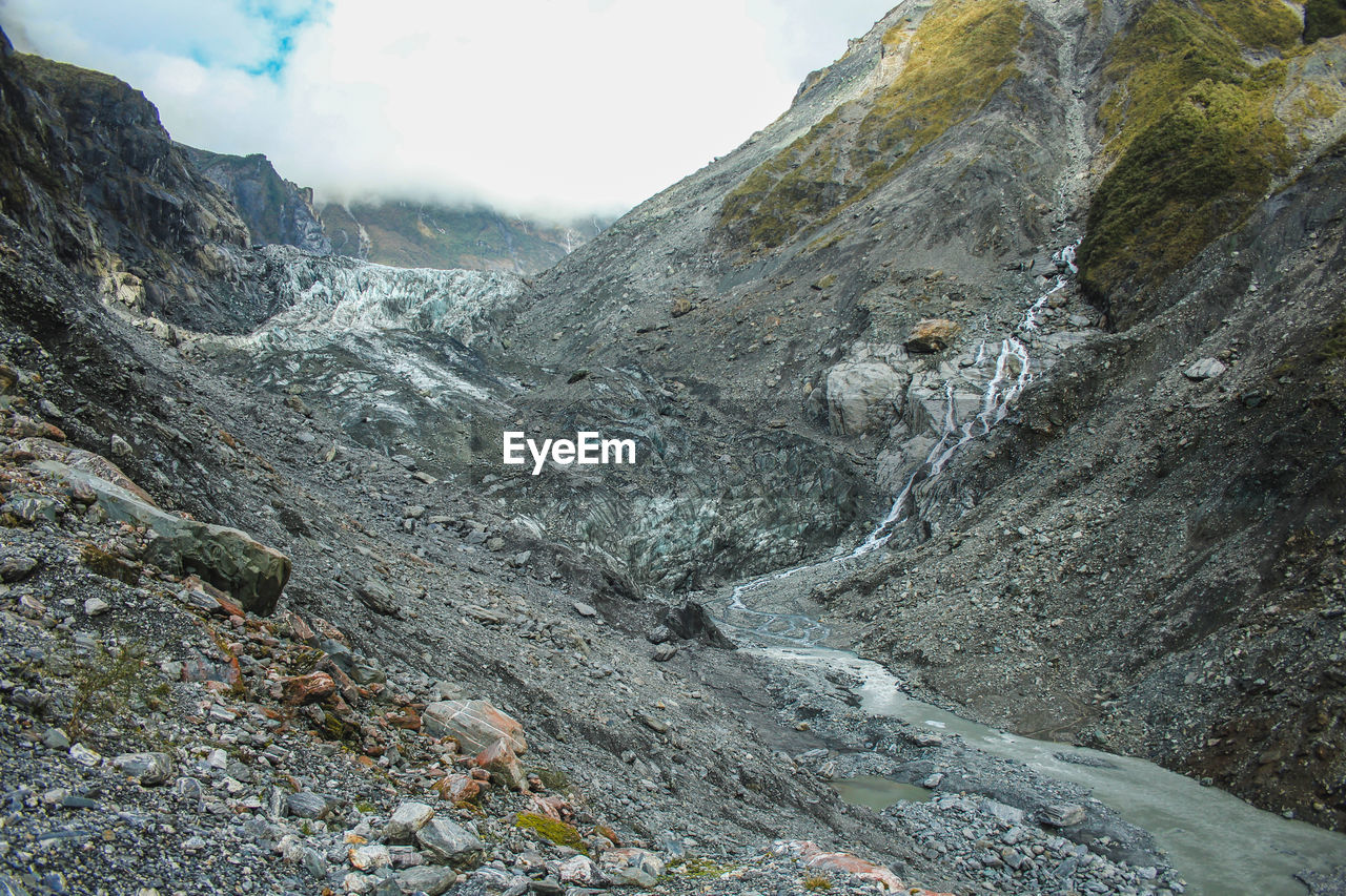 Scenic view of river flowing amidst mountains against sky