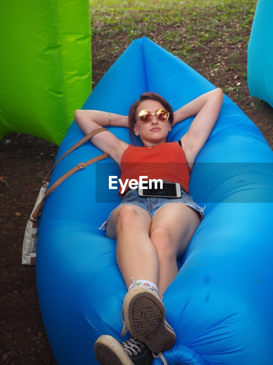 High angle view of young woman relaxing on blue inflatable seat at field