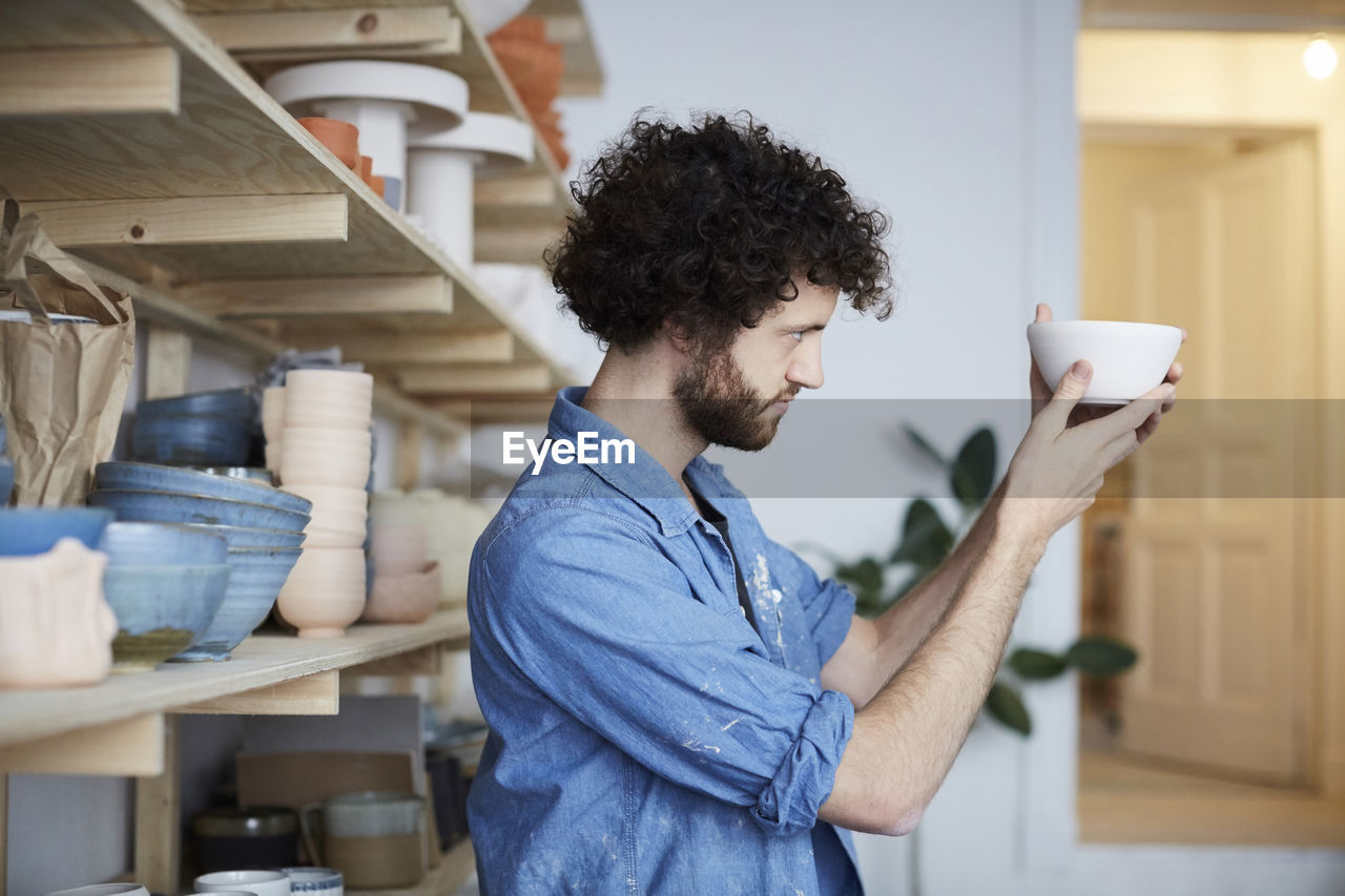 Side view of man looking at bowl in art studio