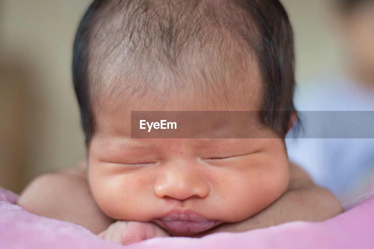 Close-up of baby girl sleeping on bed