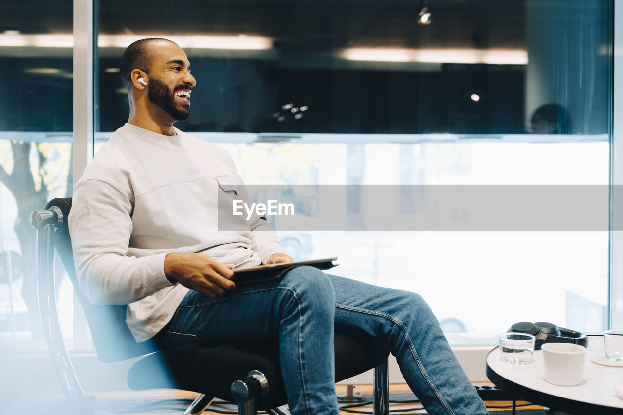 Smiling businessman with laptop sitting in office