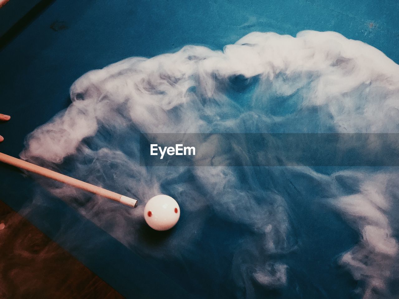High angle view of cue ball amidst smoke on pool table