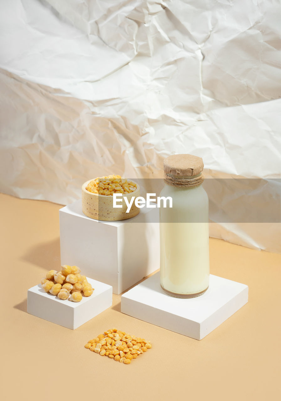 Vegetable pea milk in a bottle and chickpeas in bowl on white podium.isometric diagonal projection