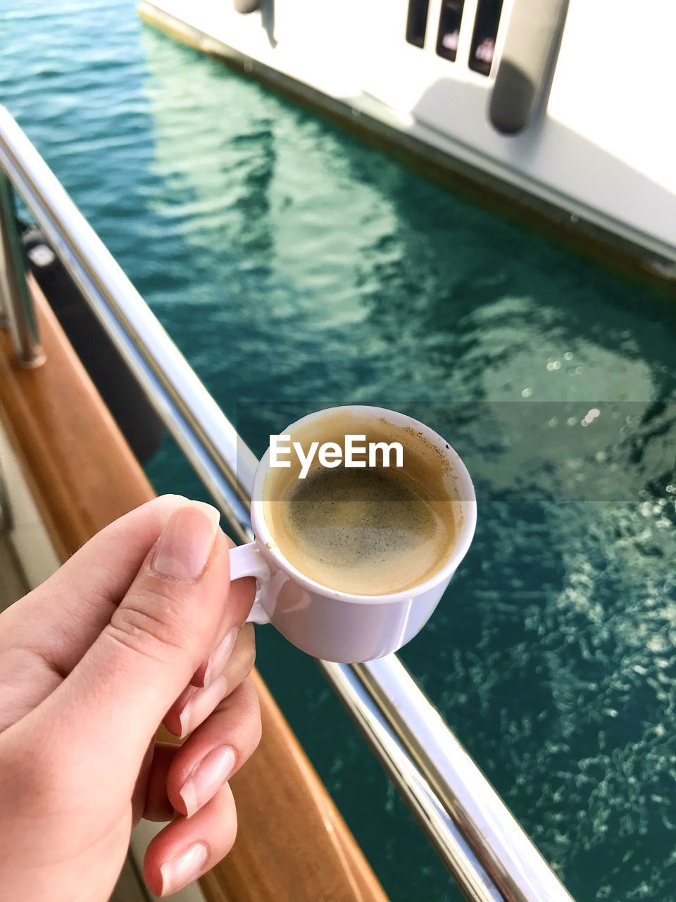 CROPPED IMAGE OF HAND HOLDING COFFEE CUP WITH WATER