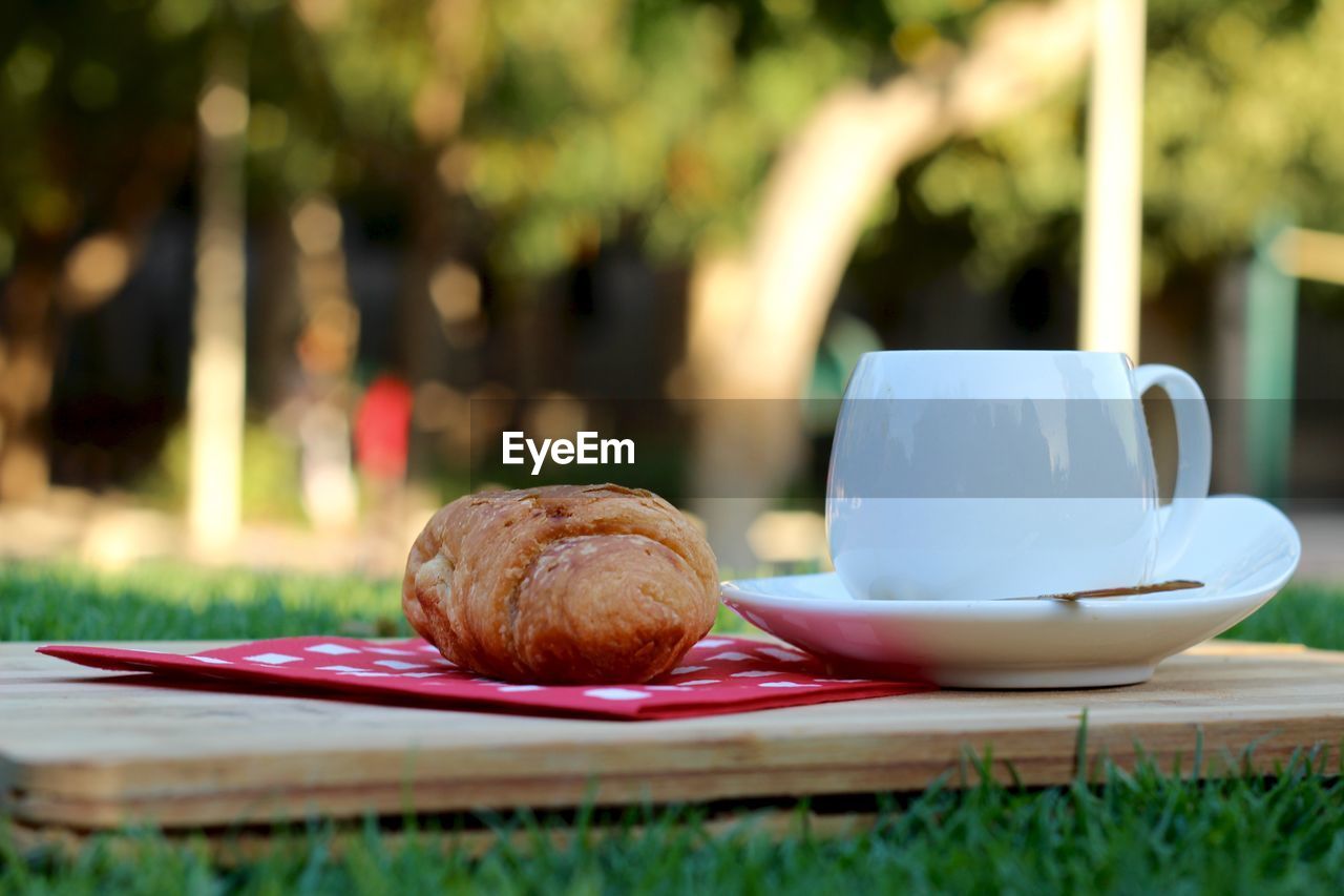 Close-up of croissant and tea cup on cutting board