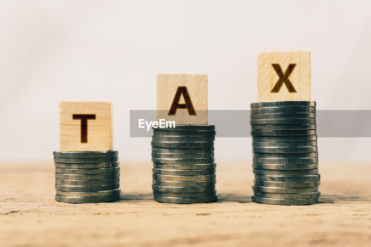 Close-up of coins with tax text against white background on table