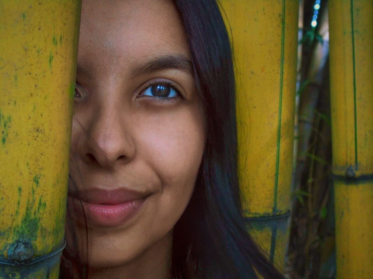 Close-up portrait of young woman standing amidst bamboo trees