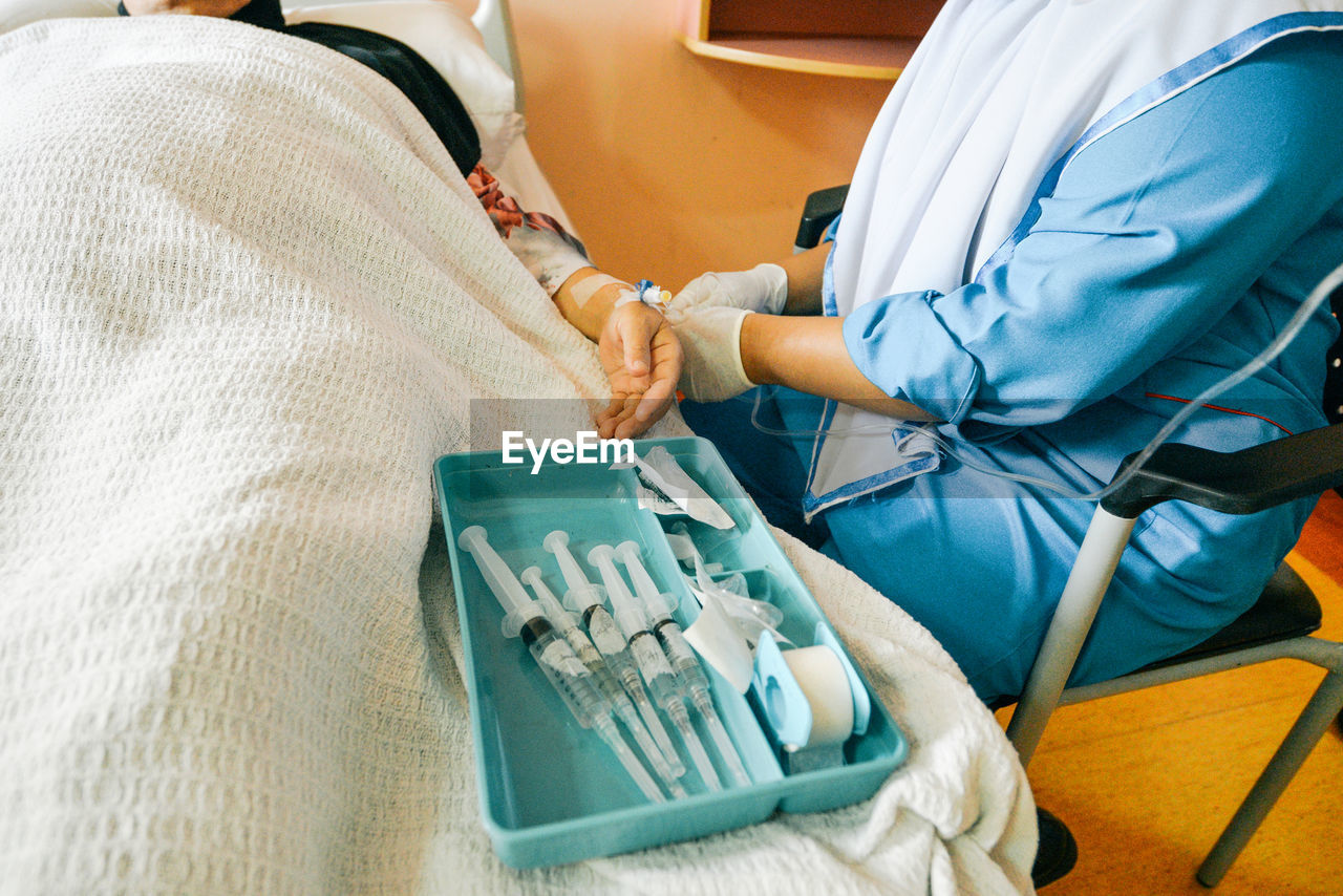 Midsection of nurse holding iv drip of patient