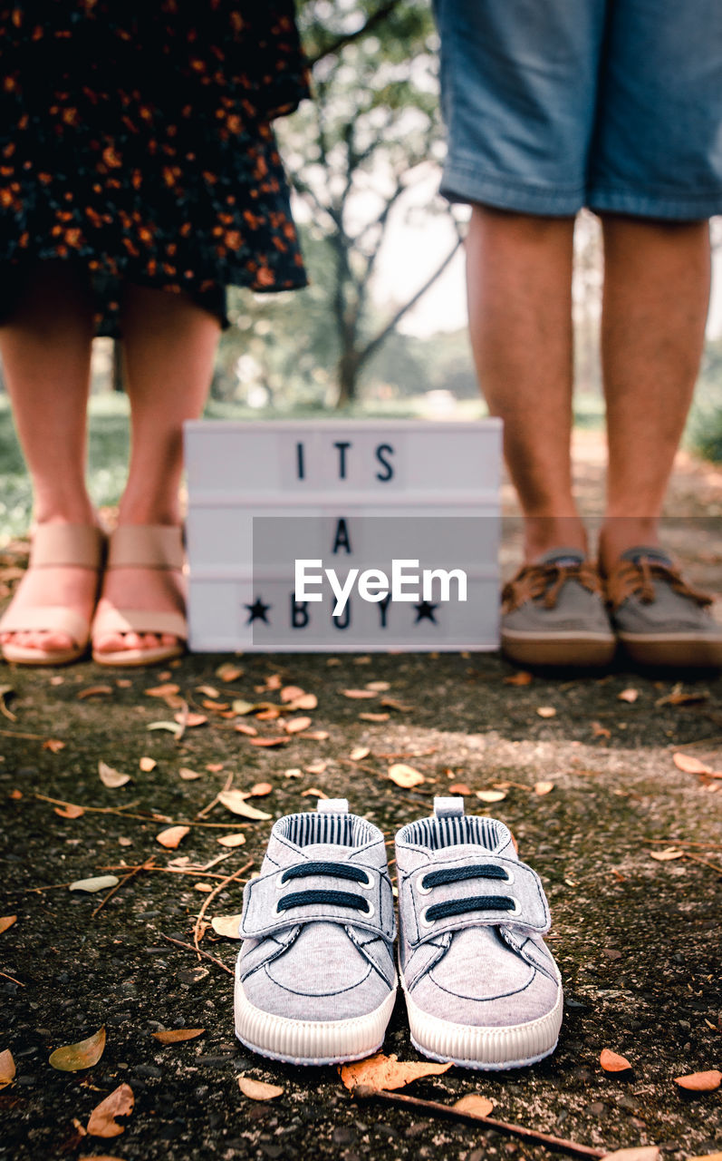 Low section of woman and man standing by text with shoes in foreground