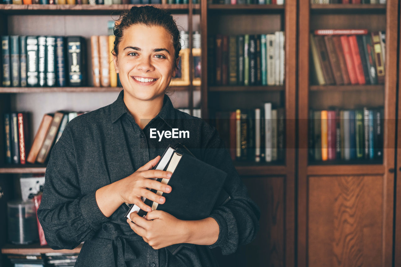 portrait of smiling young woman reading book