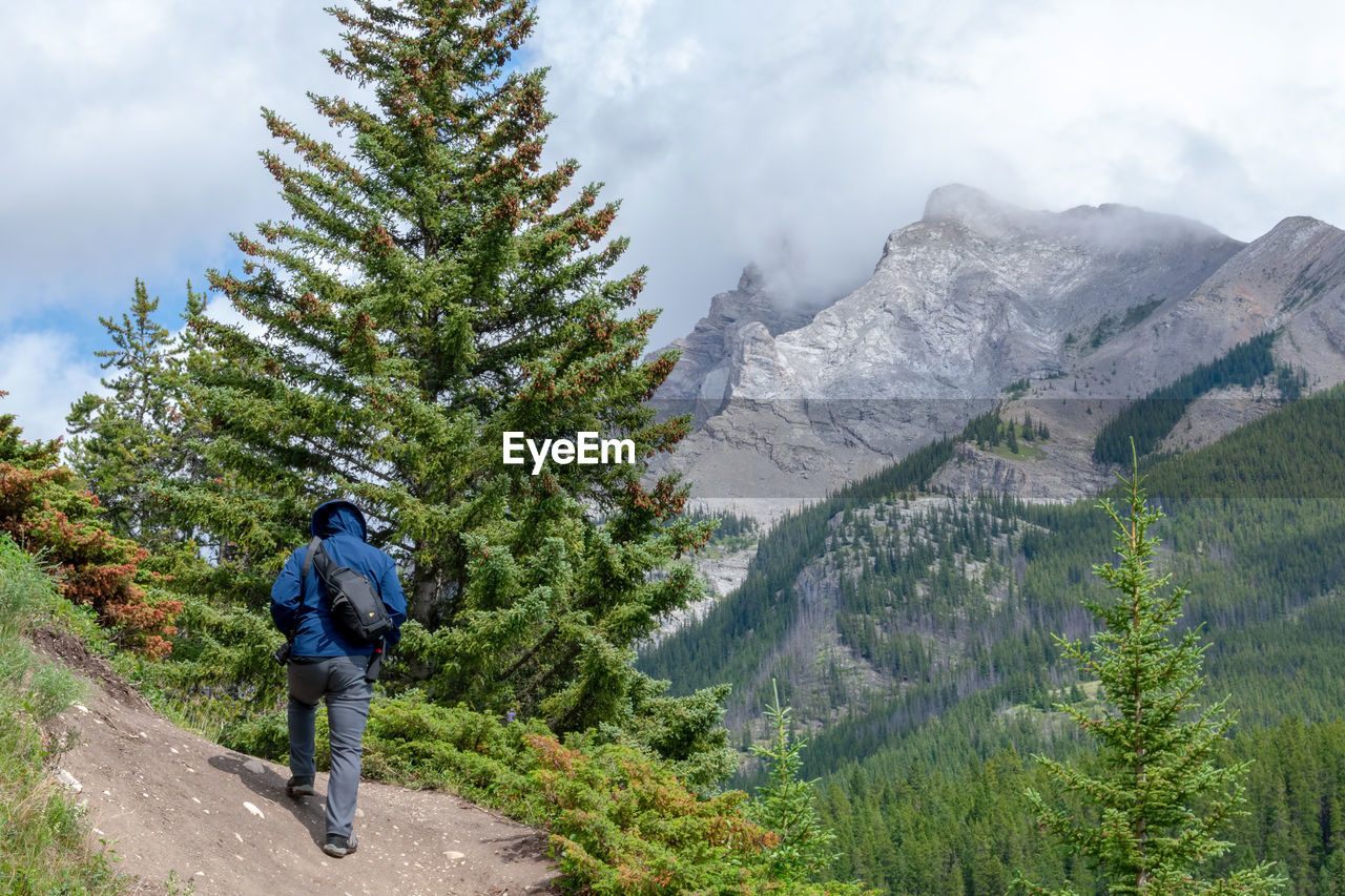 FULL LENGTH REAR VIEW OF MAN WALKING ON MOUNTAIN