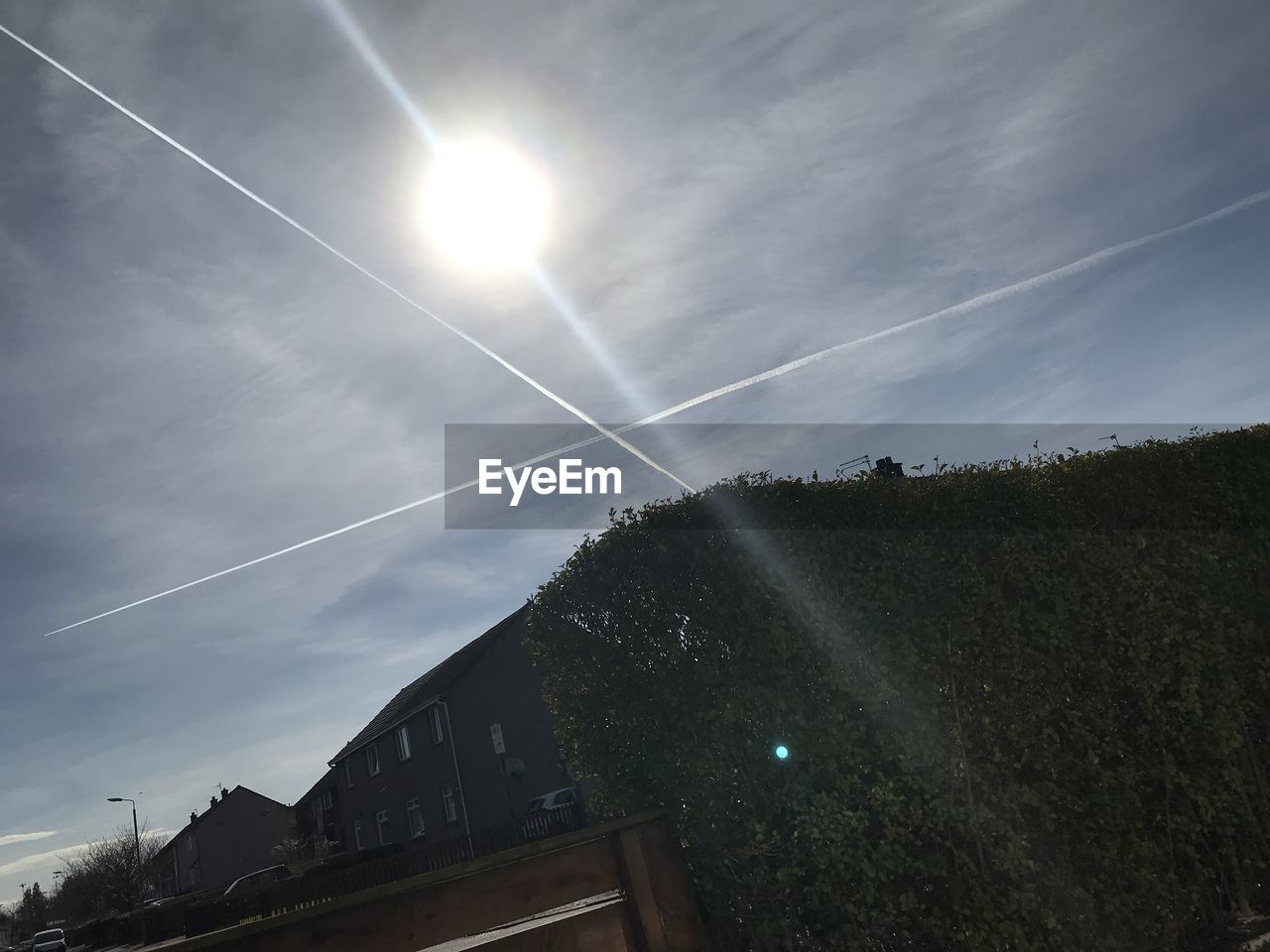 LOW ANGLE VIEW OF VAPOR TRAILS AGAINST SKY AND BUILDINGS