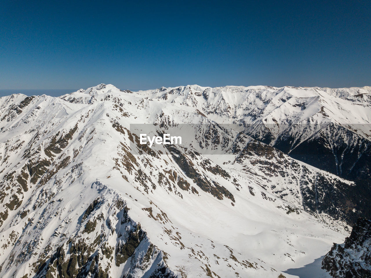 Scenic view of snowcapped mountains against clear blue sky