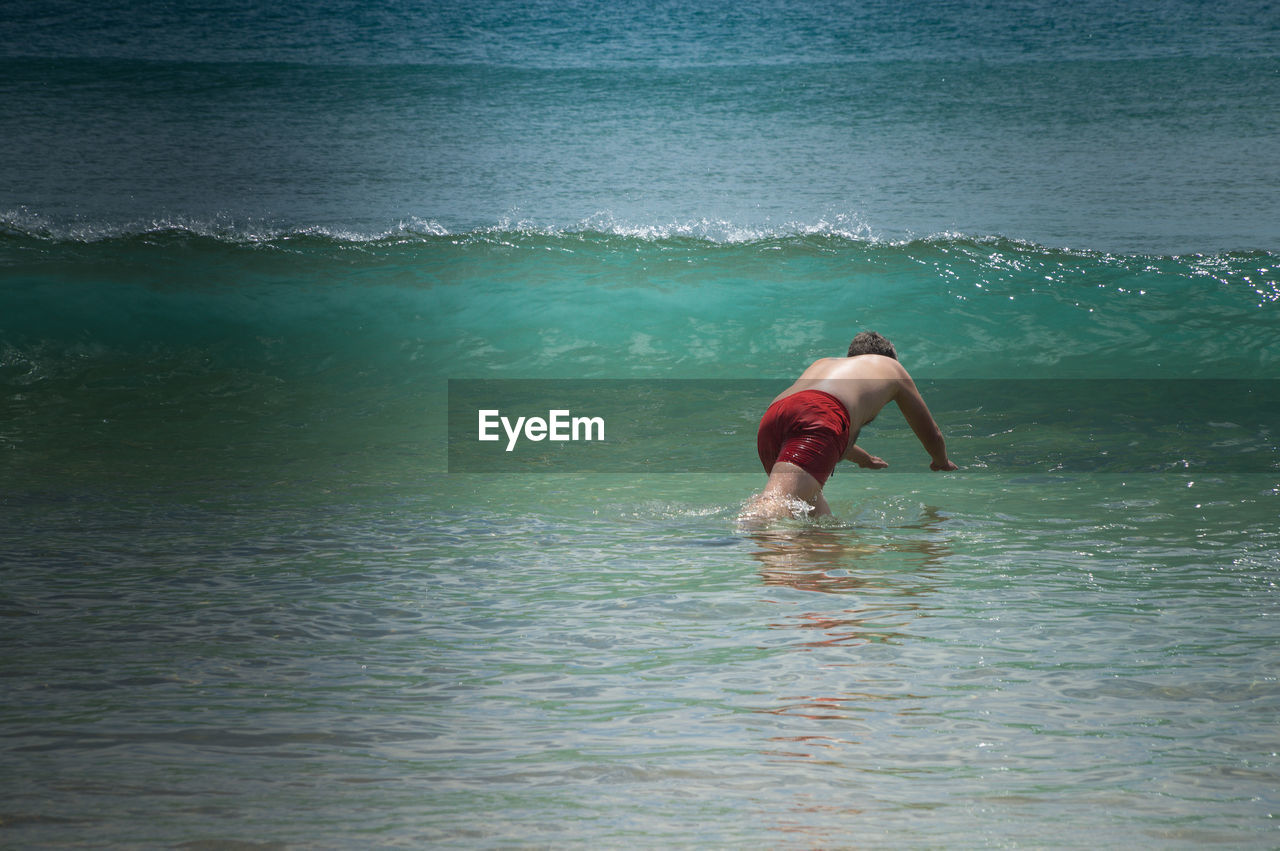 FULL LENGTH OF SHIRTLESS MAN IN SEA