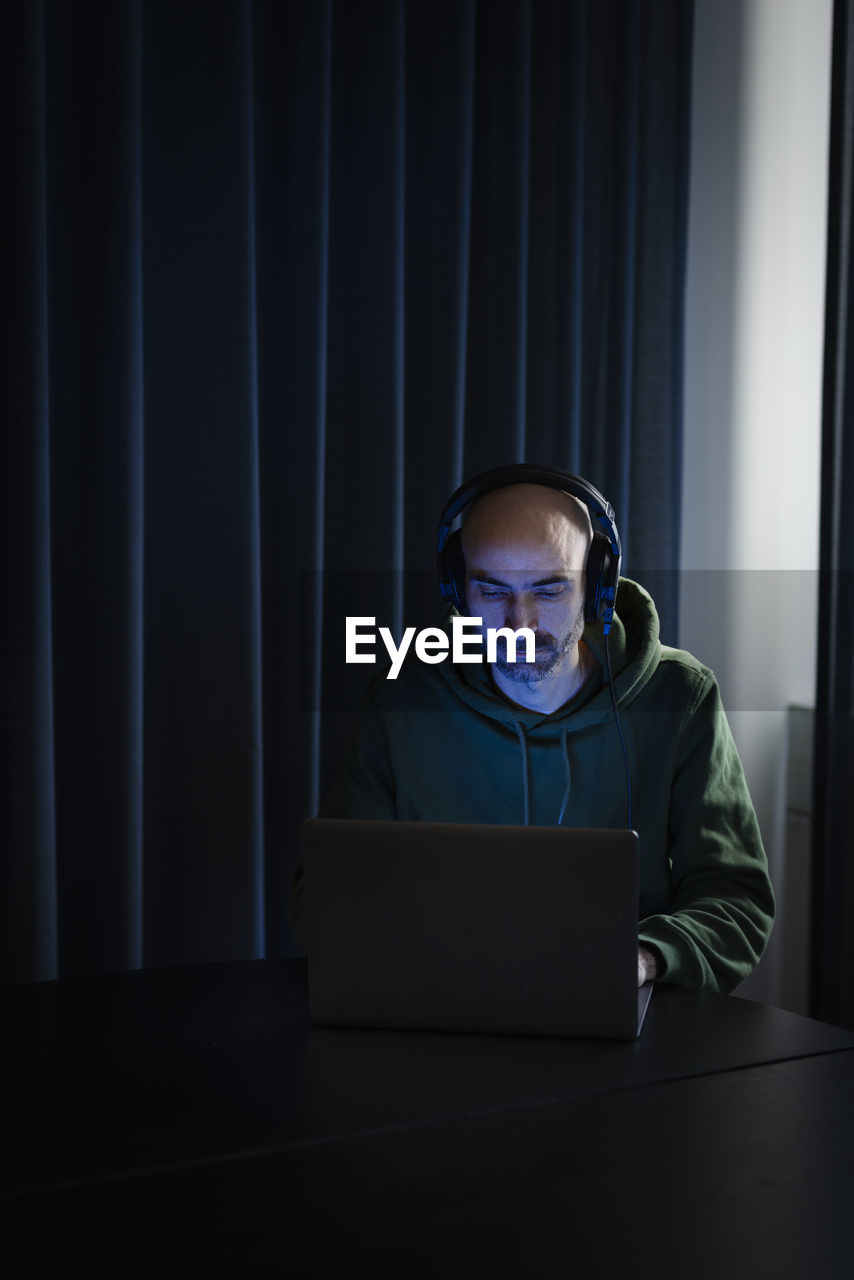 Man working on laptop in dark office