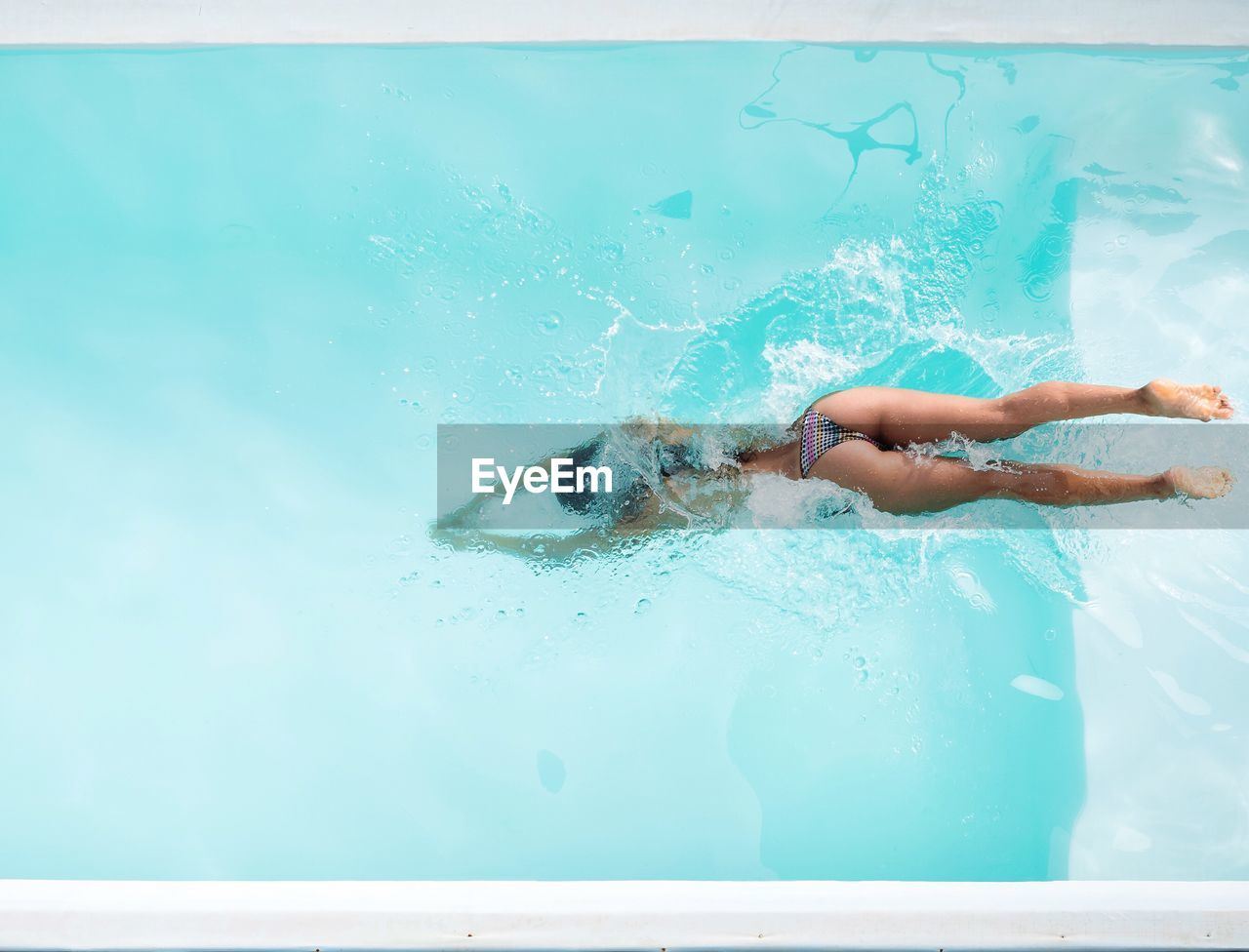 High angle view of woman wearing bikini swimming in pool on sunny day