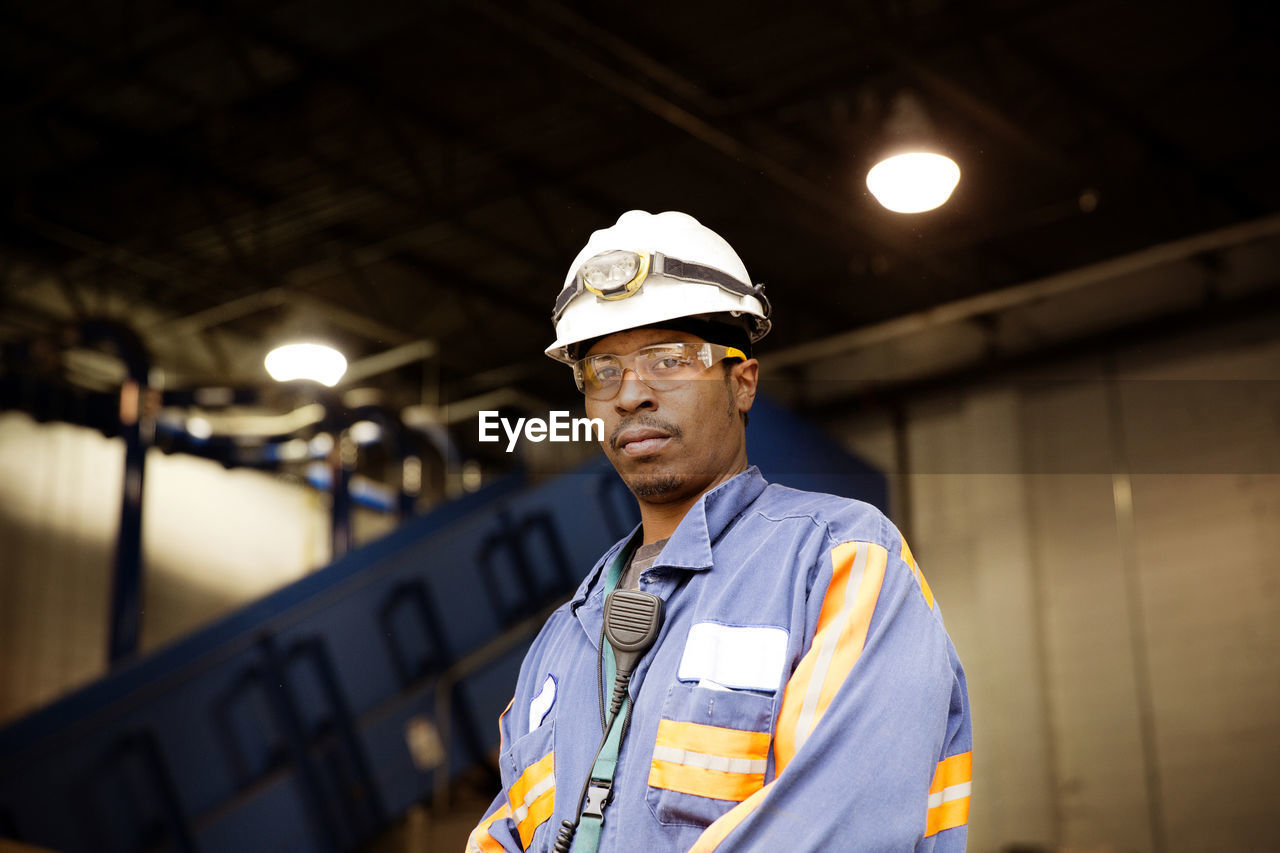 Portrait of male worker standing in illuminated recycling plant