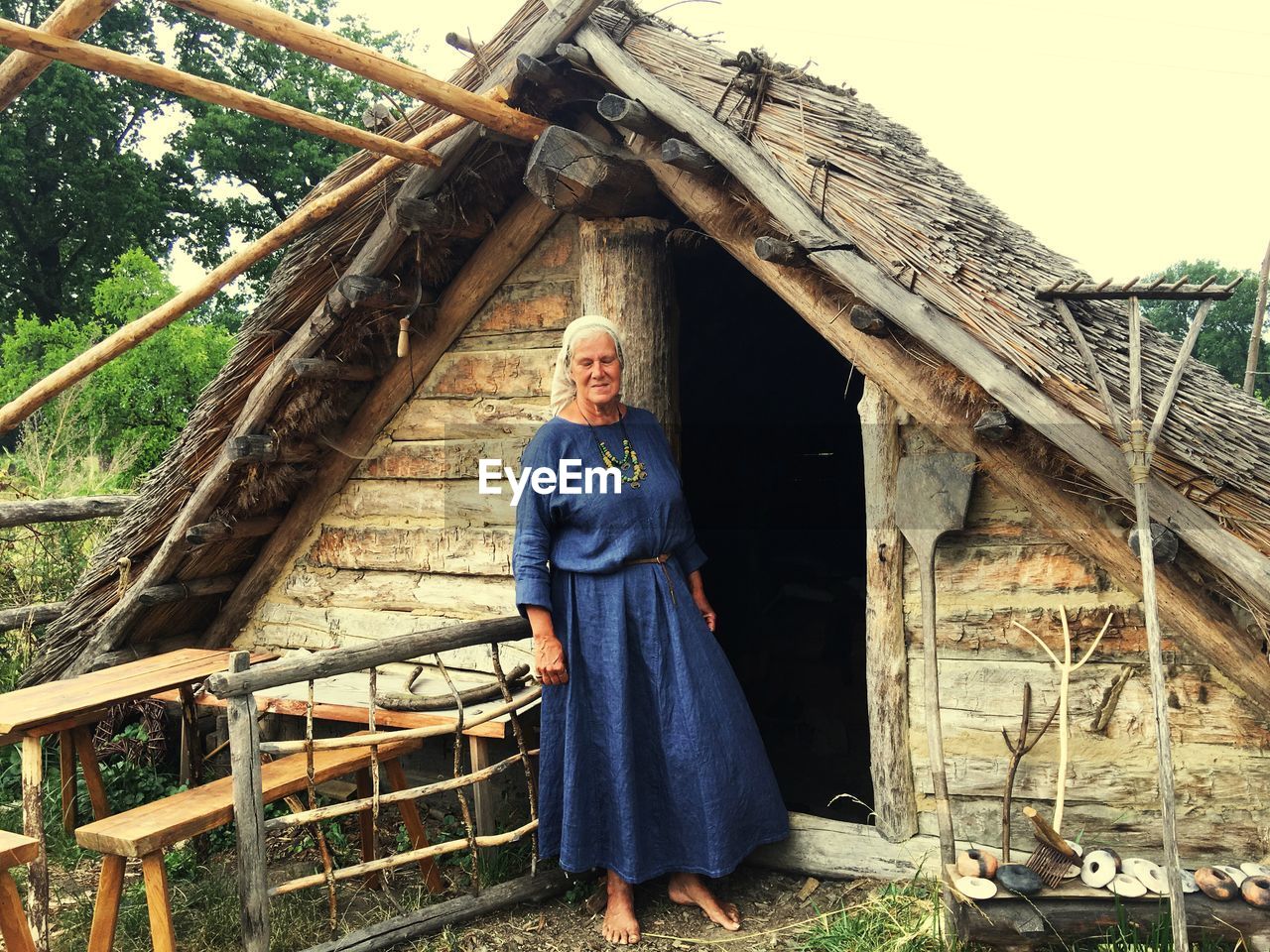 LOW ANGLE PORTRAIT OF SMILING WOMAN STANDING ON HOUSE