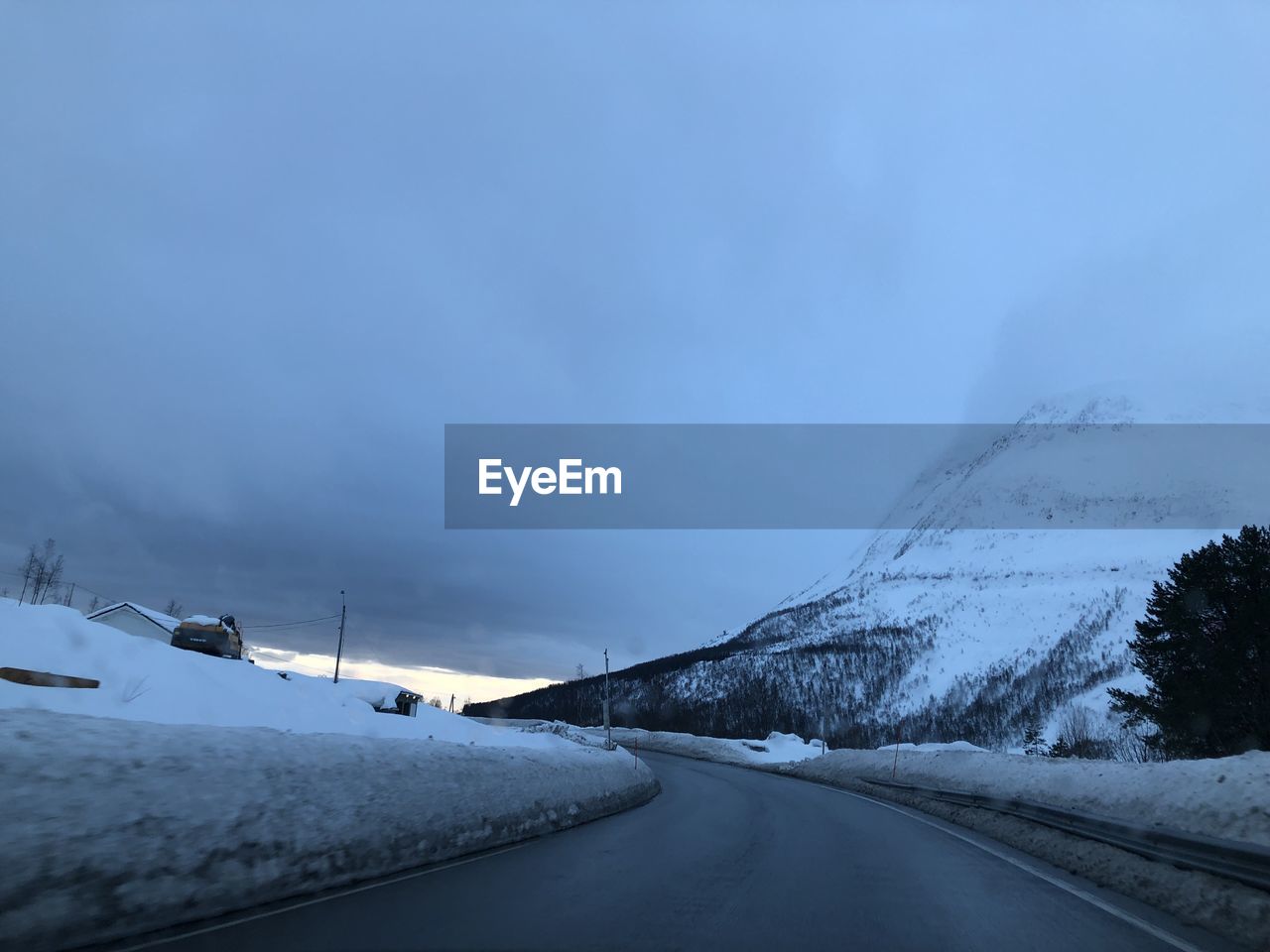 Road by snow covered mountain against sky