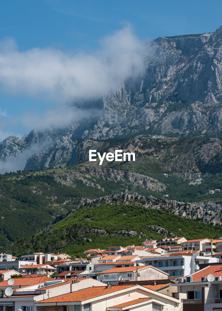 Aerial view of townscape by mountain against sky