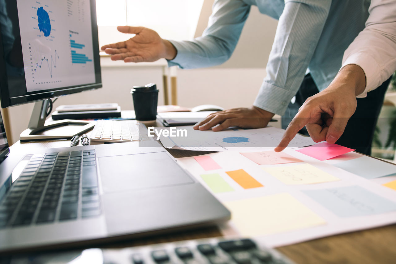 Midsection of business people working on table