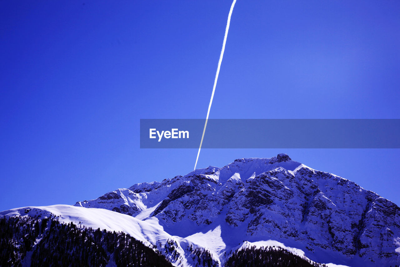 LOW ANGLE VIEW OF SNOWCAPPED MOUNTAINS AGAINST BLUE SKY