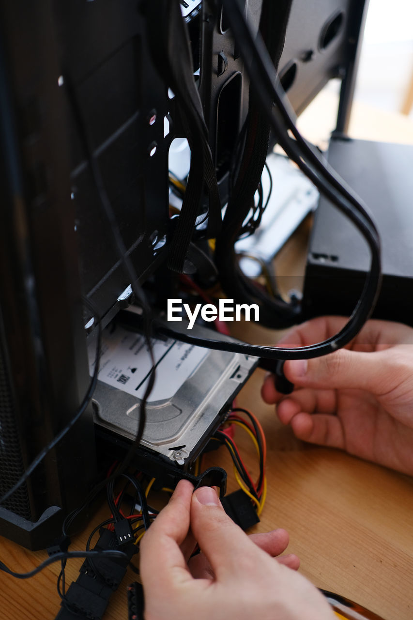 Hands of young male master install parts of pc into case.