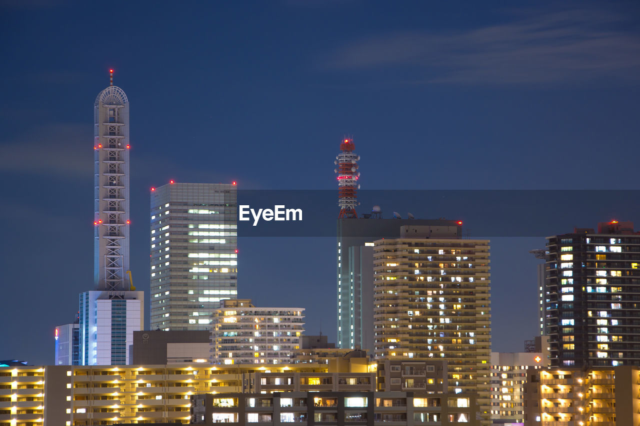 Illuminated buildings in city against sky at night