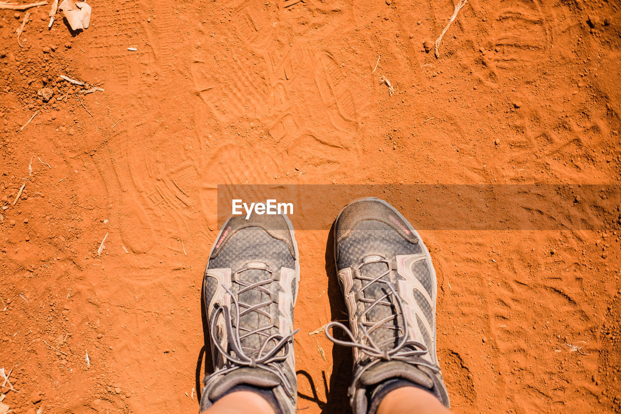 Low section of man standing on dirt road