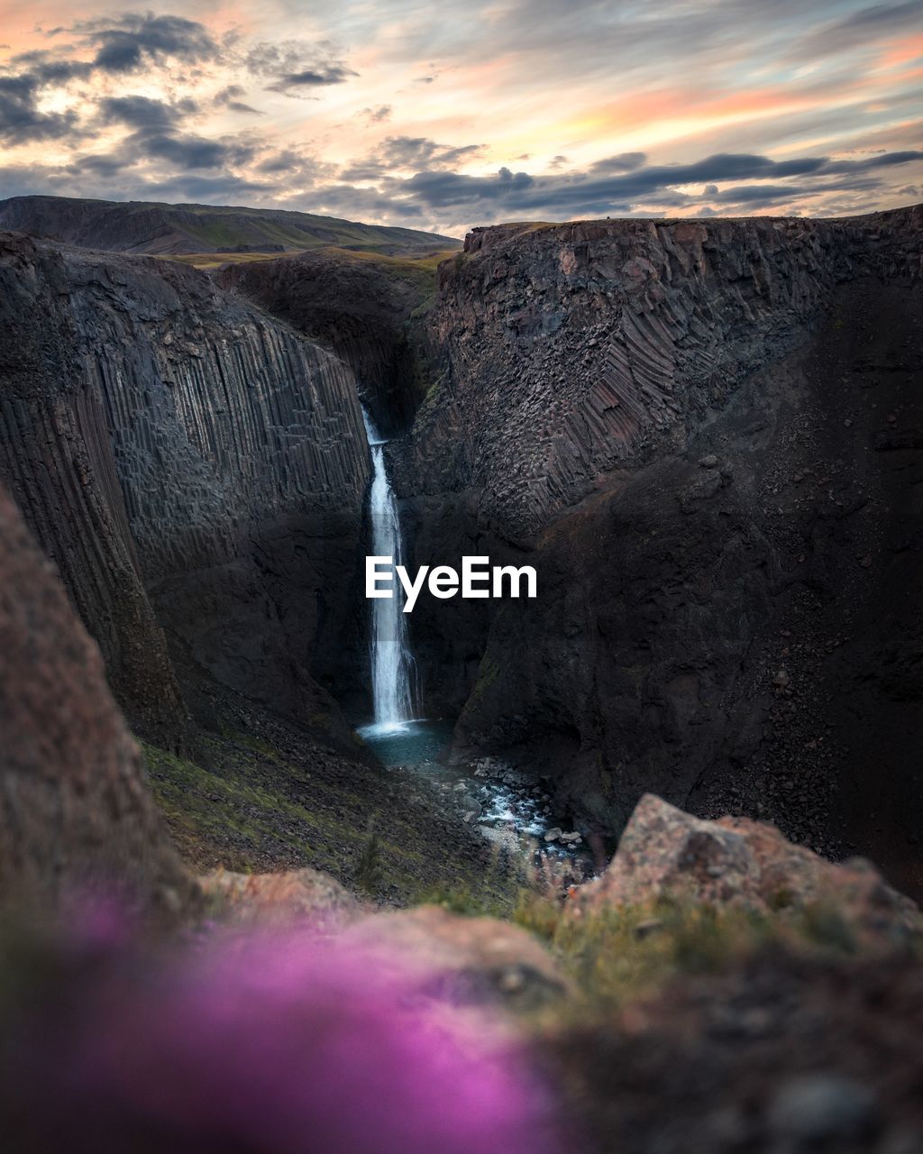 Scenic view of waterfall against sky during sunset