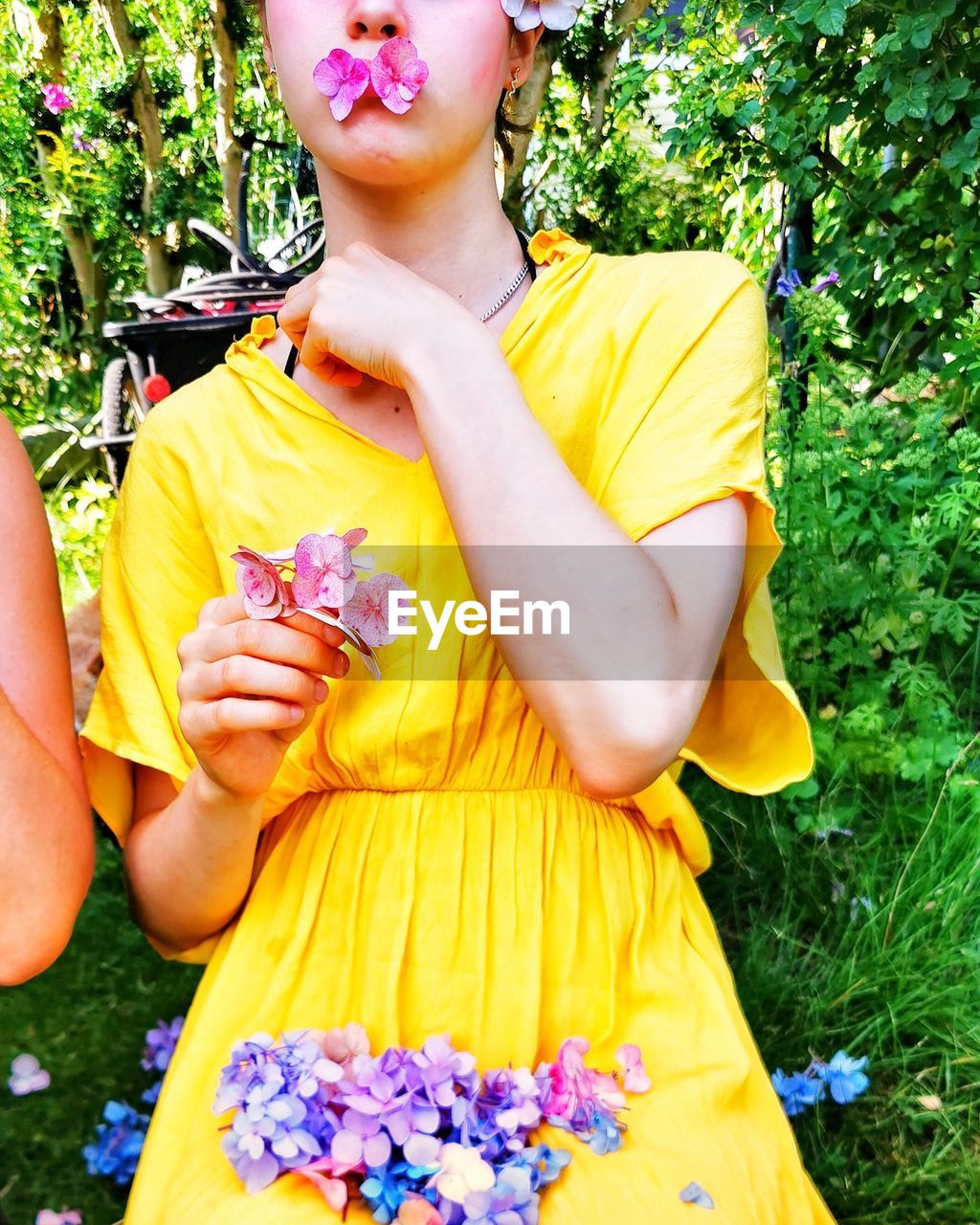 LOW SECTION OF WOMAN HOLDING YELLOW FLOWER